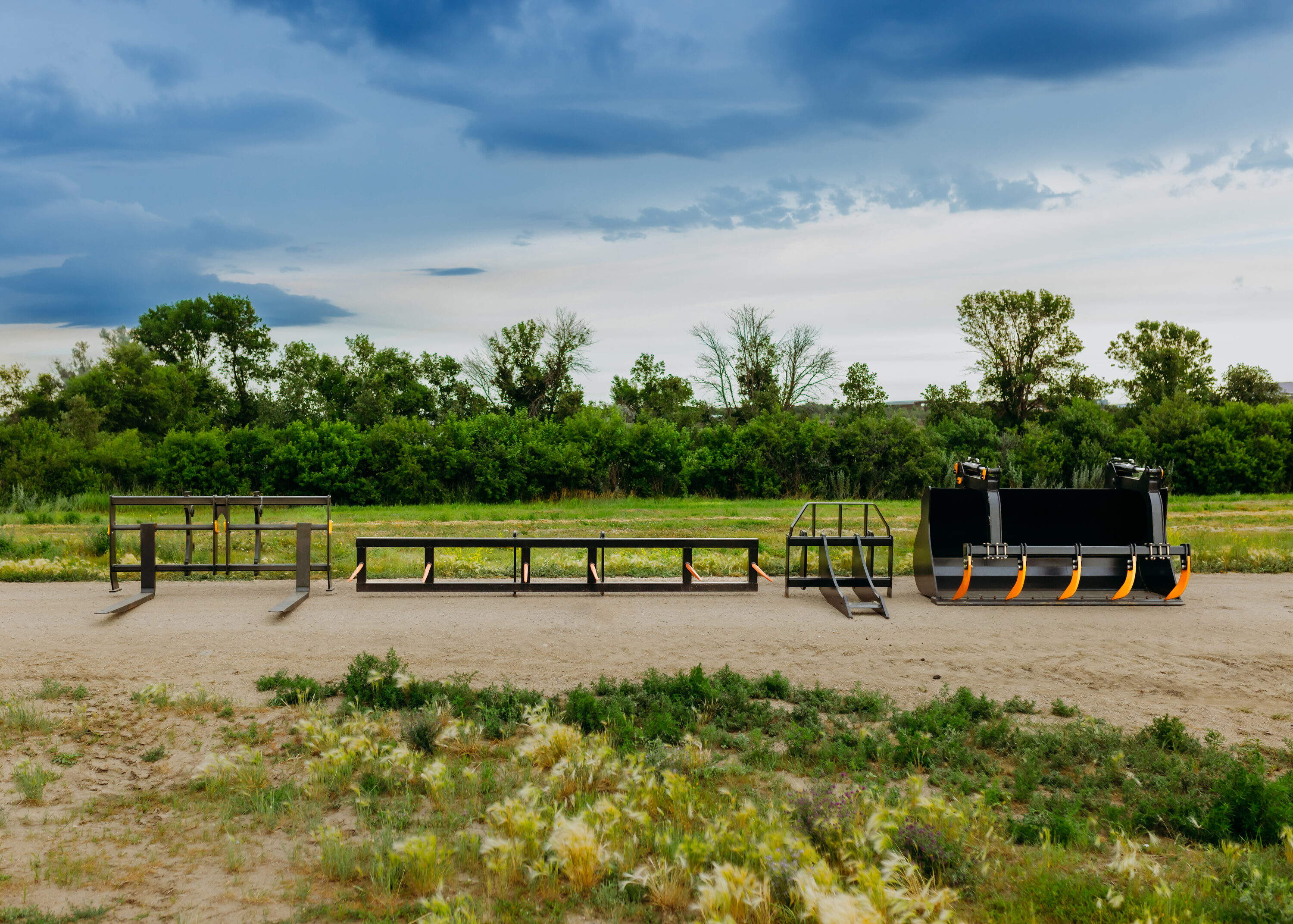 Panova wheel loader buckets, forks, and attachments lined up in a South Dakota field